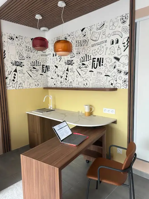 Espace de consultation : bureau en bois et plan de travail en marbre sous une fresque graphique colorée, baigné de lumière.