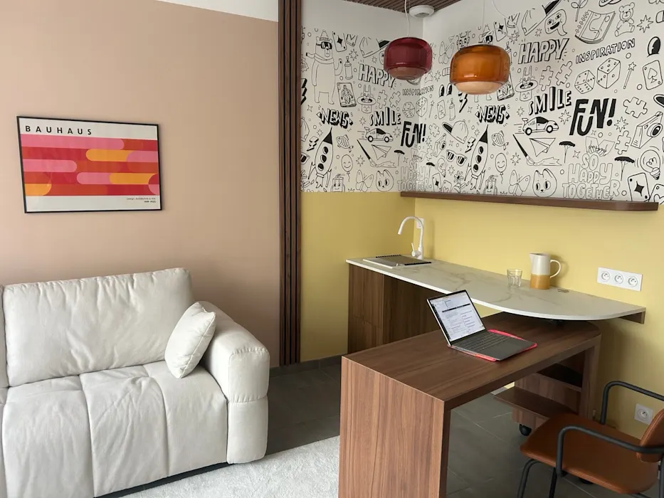 Vue d'ensemble du cabinet : canapé crème, affiche Bauhaus et coin bureau chaleureux.
